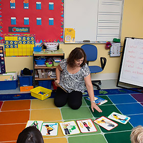 teacher on floor with teaching materials